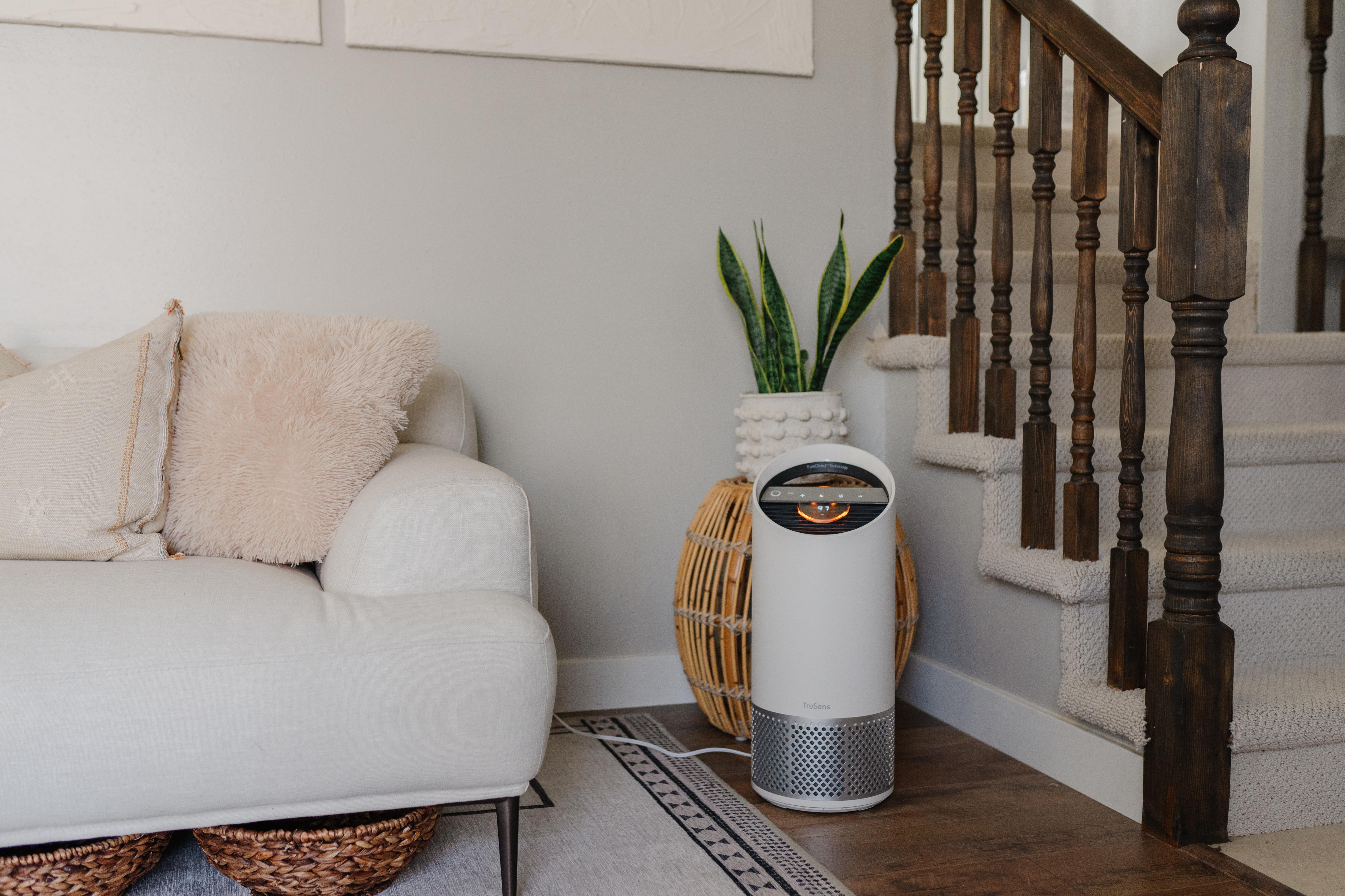 TruSens Air Purifier in a living room, next to a couch and staircase. 