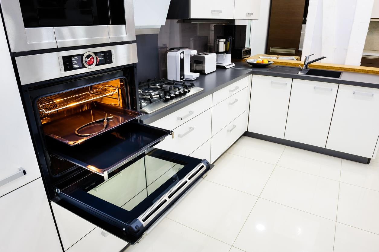 Modern kitchen with upgraded technology, white cabinets, and grey countertops. 