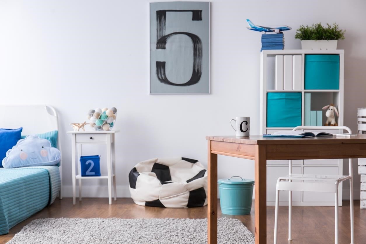 Kid's bedroom with toys, a desk, and a bean bag chair. 