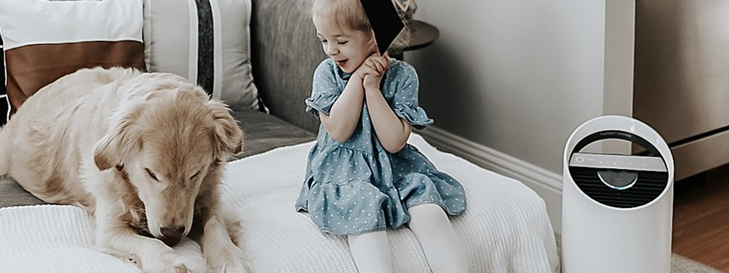 Little girl smiling at her dog, next to a TruSens Air Purifier.