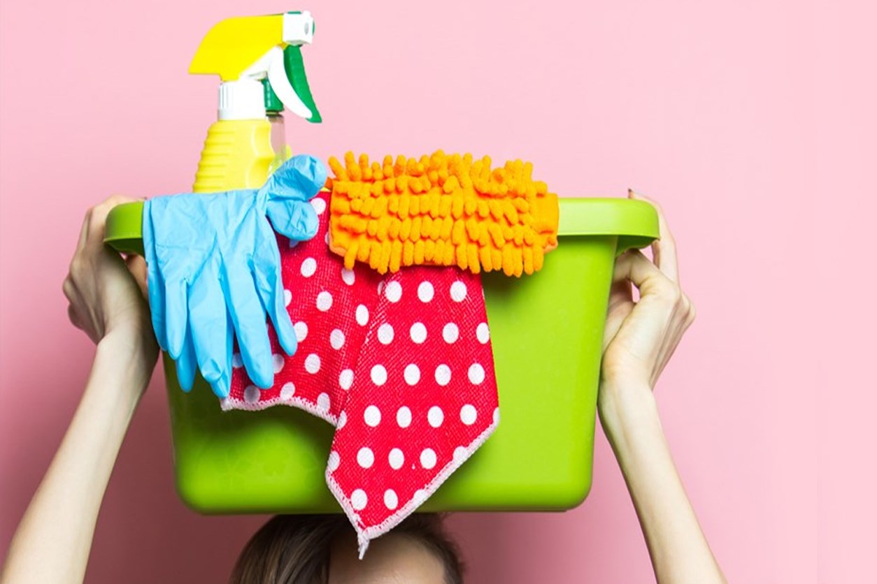 Person lifting a basket of cleaning supplies above their head. 