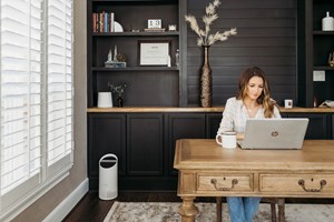 Woman sitting at her desk with small air purifier on the floor