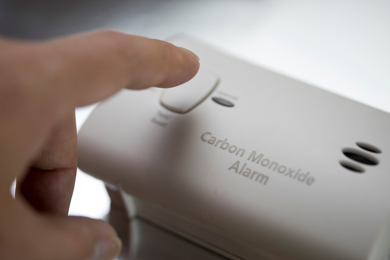 Person pressing button on a carbon monoxide alarm. 