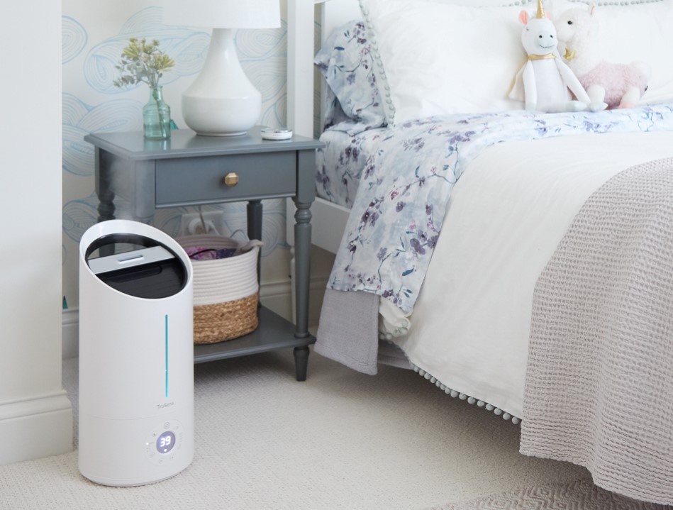Humidifier sitting next to a bed and bedside table