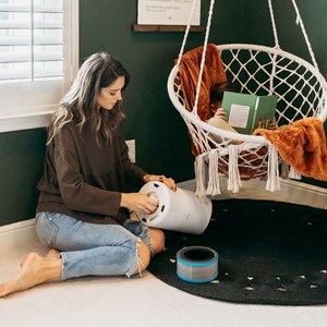 Woman sitting in room changing filter in small air purifier
