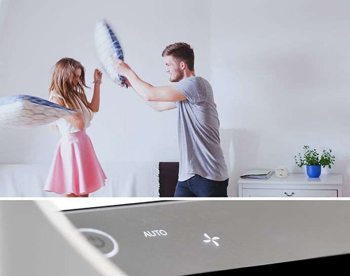 Woman and man having a pillow fight. TruSens Air Purifier control panel on auto.