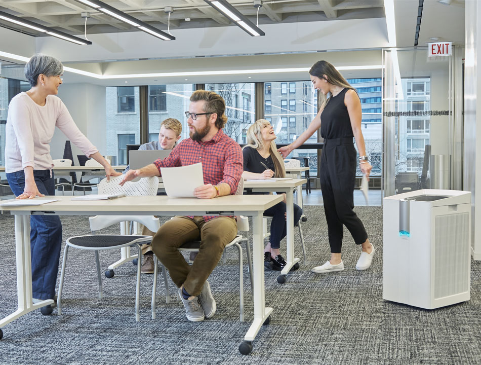 Workers collaborating in a shared work space with a  performance air purifier in the room